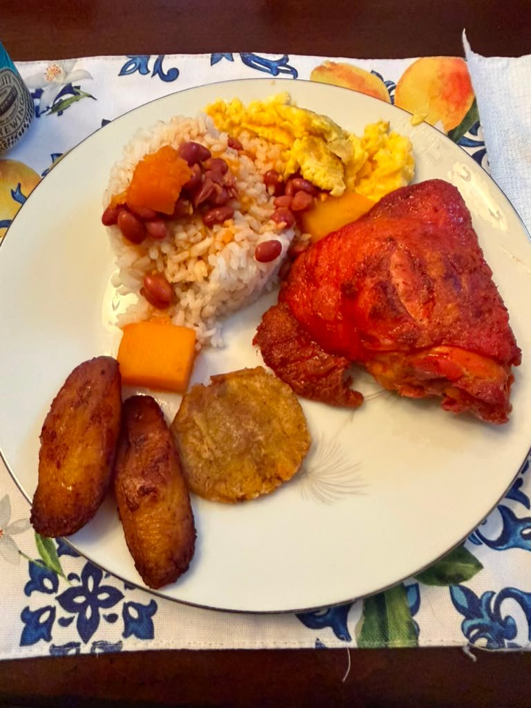 Rice and beans with chicken thigh, fried plantains and eggs made by Anissa